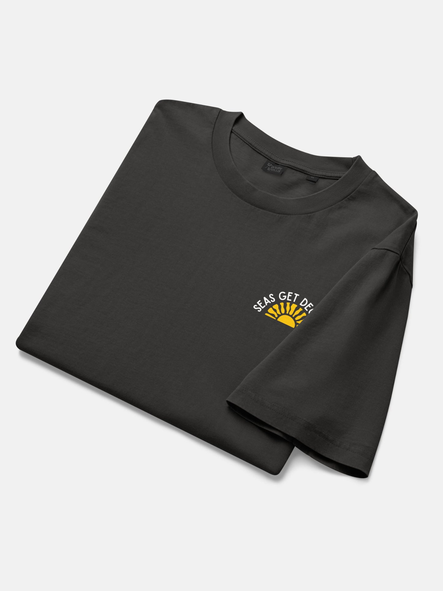 Golden Tide Tee folded flat lay in black rock — Seas Get Degrees