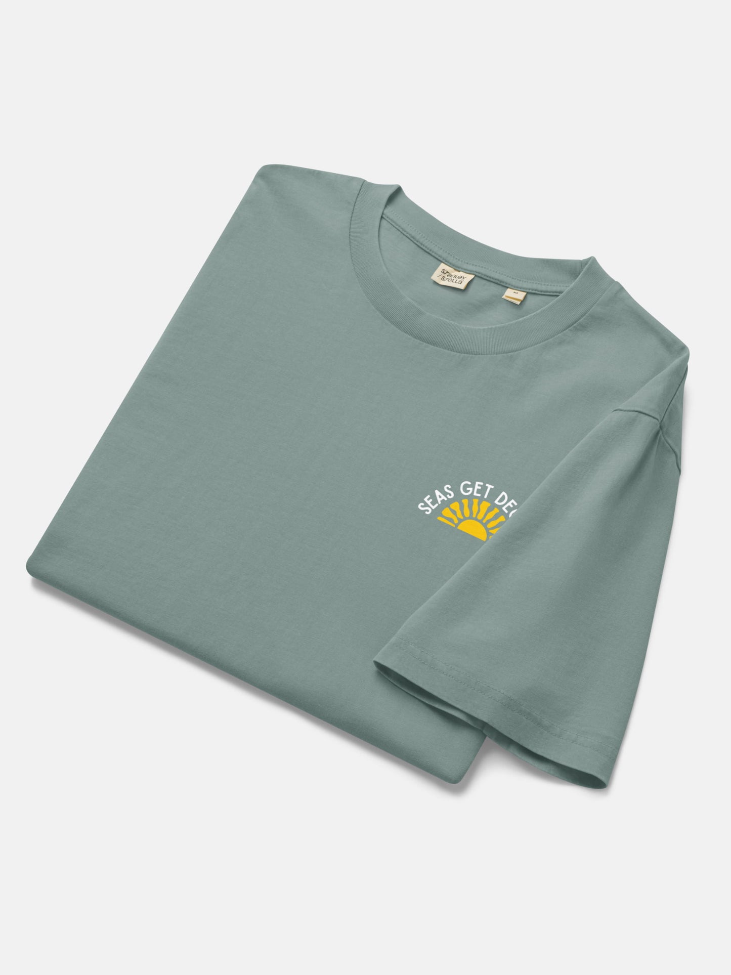 Golden Tide Tee folded flat lay in green bay — Seas Get Degrees