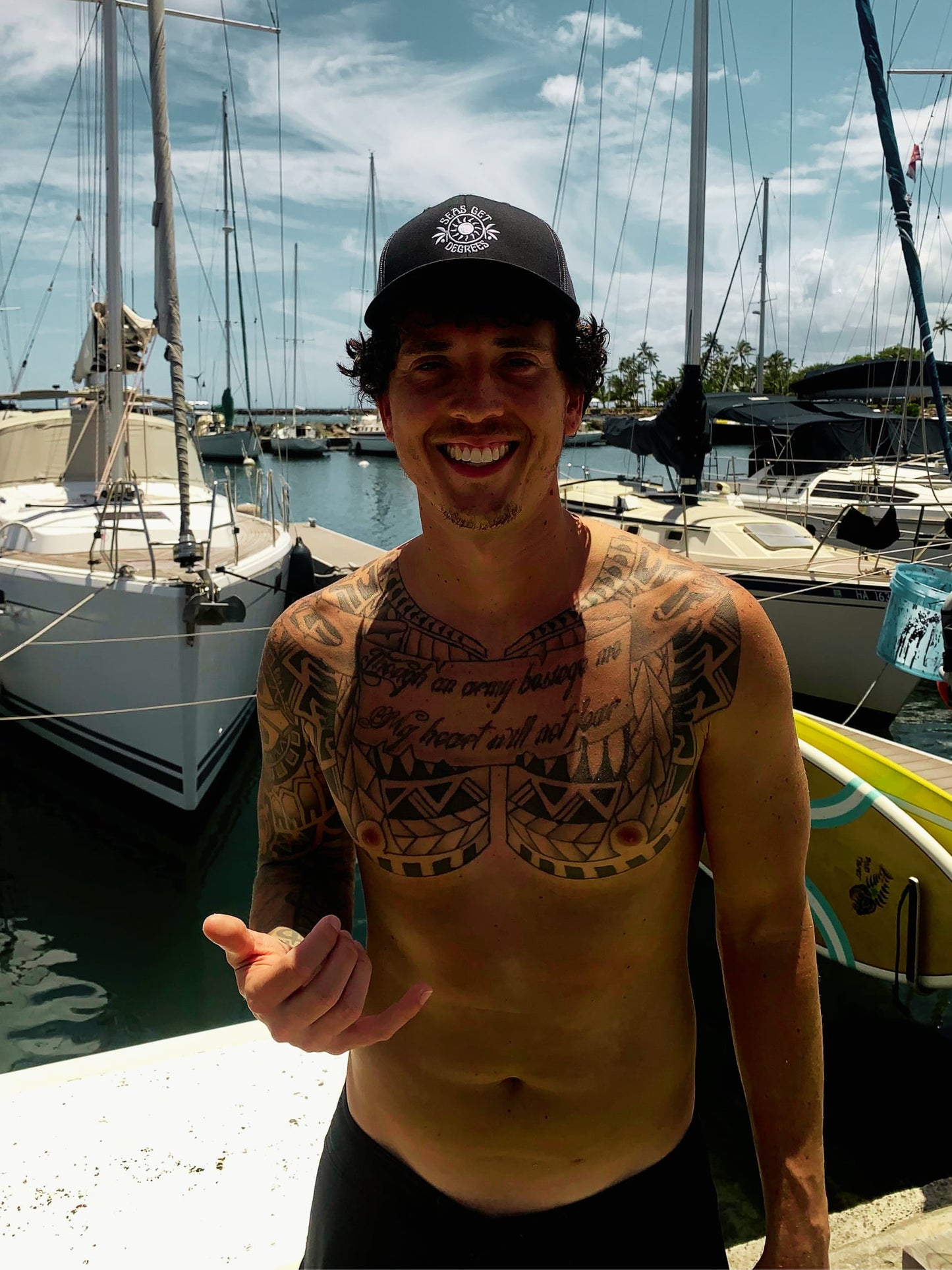 Sun and Shade Trucker Hat worn at boat harbor with shaka in black and charcoal — Seas Get Degrees lifestyle